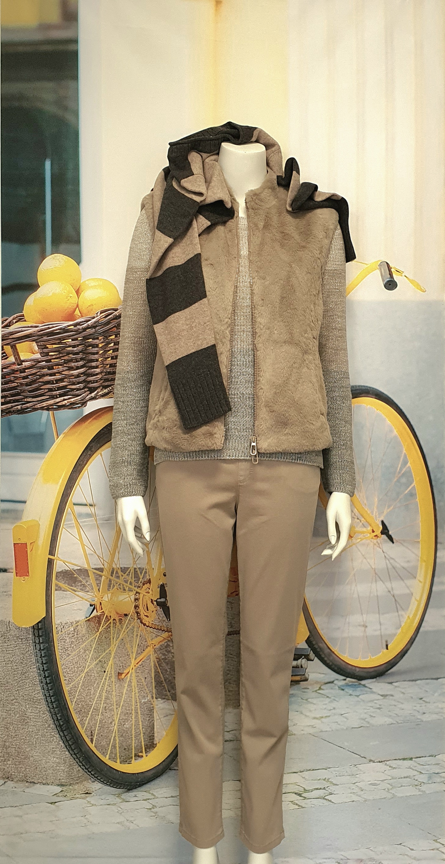 Herbst/Winter 2025 - Beiger Strickpullover mit Weste und schwarz-beige gestreiften Pullover über den Schultern