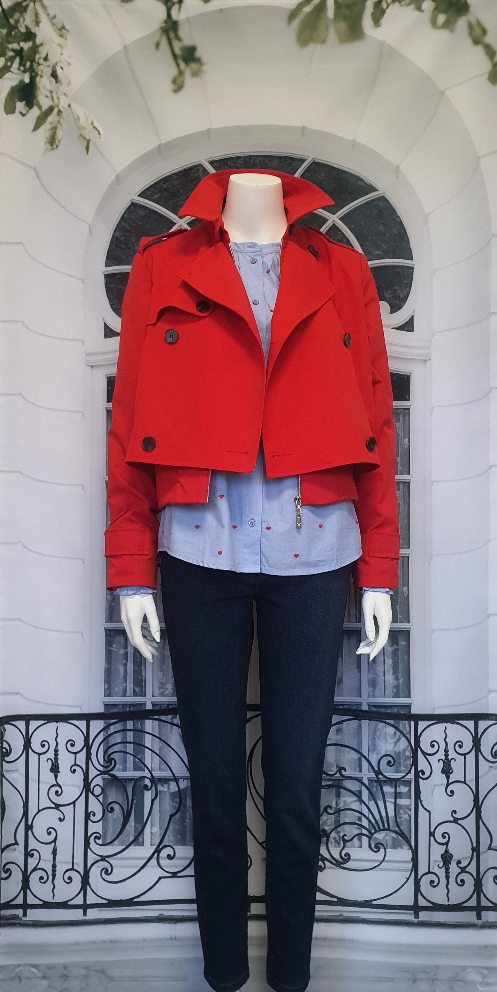 Frühjahr/Sommer 2026 - hellblaue Bluse mit roten Stickereien, dunkelblaue Jeans und einem roten kurzen Trenchcoat