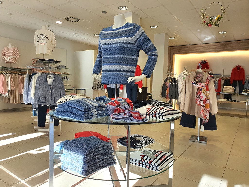 Verkaufstisch mit Kleidung, auf dem eine männliche Schaufensterpuppe steht