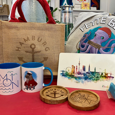 Verschiedene Produkte aus dem elbstolz-Portfolio: Tassen, lasergravierte Untersetzer, Frühstücksbrett, Taschen