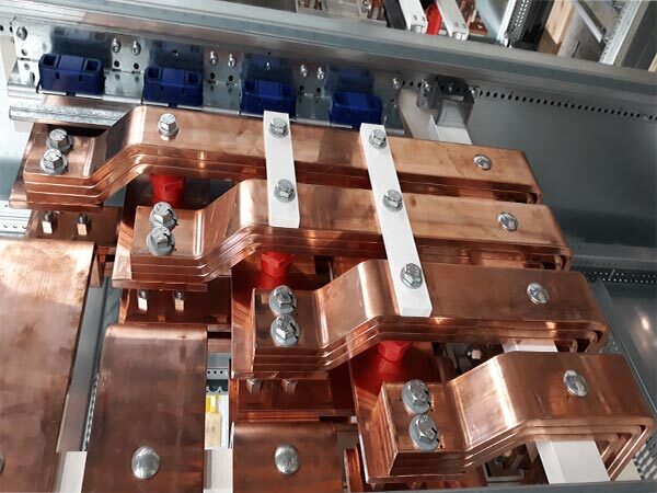 Kupferne Stromschienen mit Schraubverbindungen in einem elektrischen Schaltkasten.