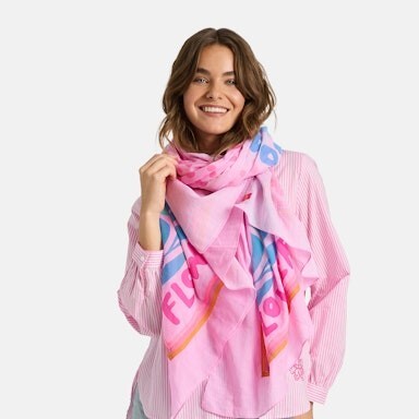 Due F/S 2026 - rosanes Tuch mit blauen und pinken Details, da drunter ein rosanes Oberteil und eine helle Jeans