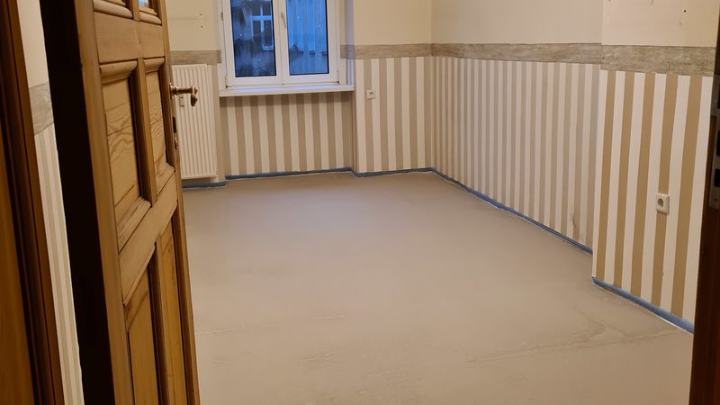 Ausgießen der Bodenfläche Nivellierestrich. Bearbeiten des Fliesenspiegels mit einen Fliesenfarbsystem.